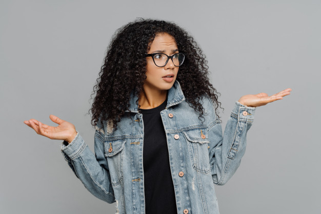 afro-woman-with-crisp-hair-raises-hands-bewilderment-looks-aside_95891-91